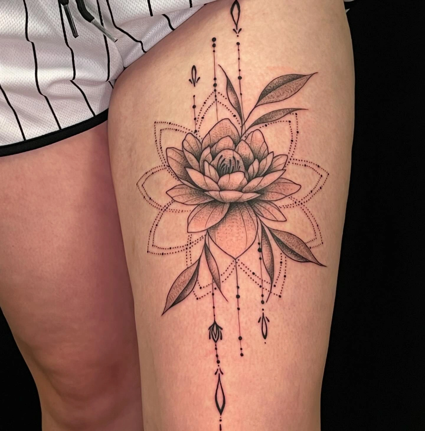 Tatuaj detaliat cu floare și elemente geometrice pe coapsă