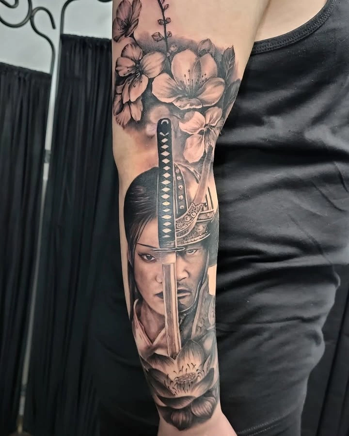 Tatuaj pe braț cu portret de samurai și flori