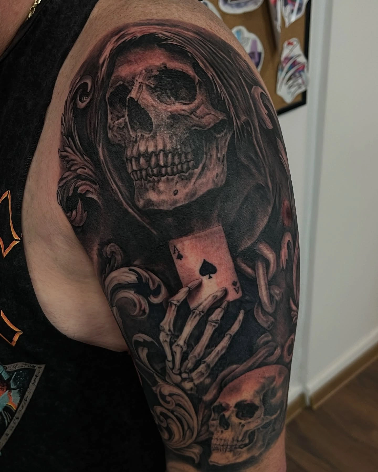 Tatuaj cu craniu și mână scheletică ținând o carte de joc