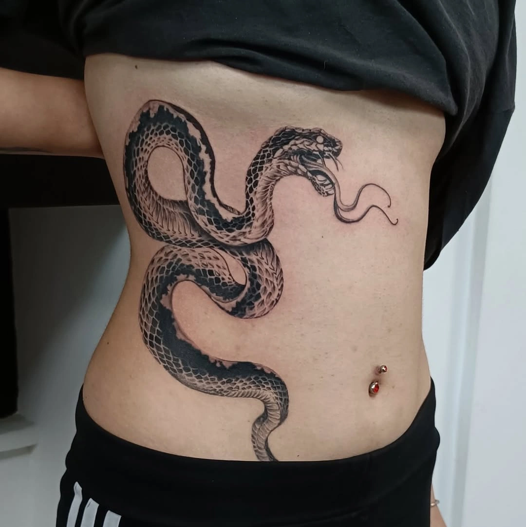 Tatuaj detaliat cu un șarpe încolăcit pe partea laterală a corpului.