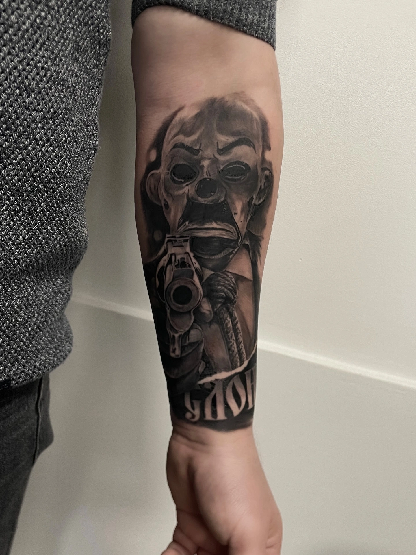 Tatuaj pe antebraț cu mască înfricoșătoare și pistol