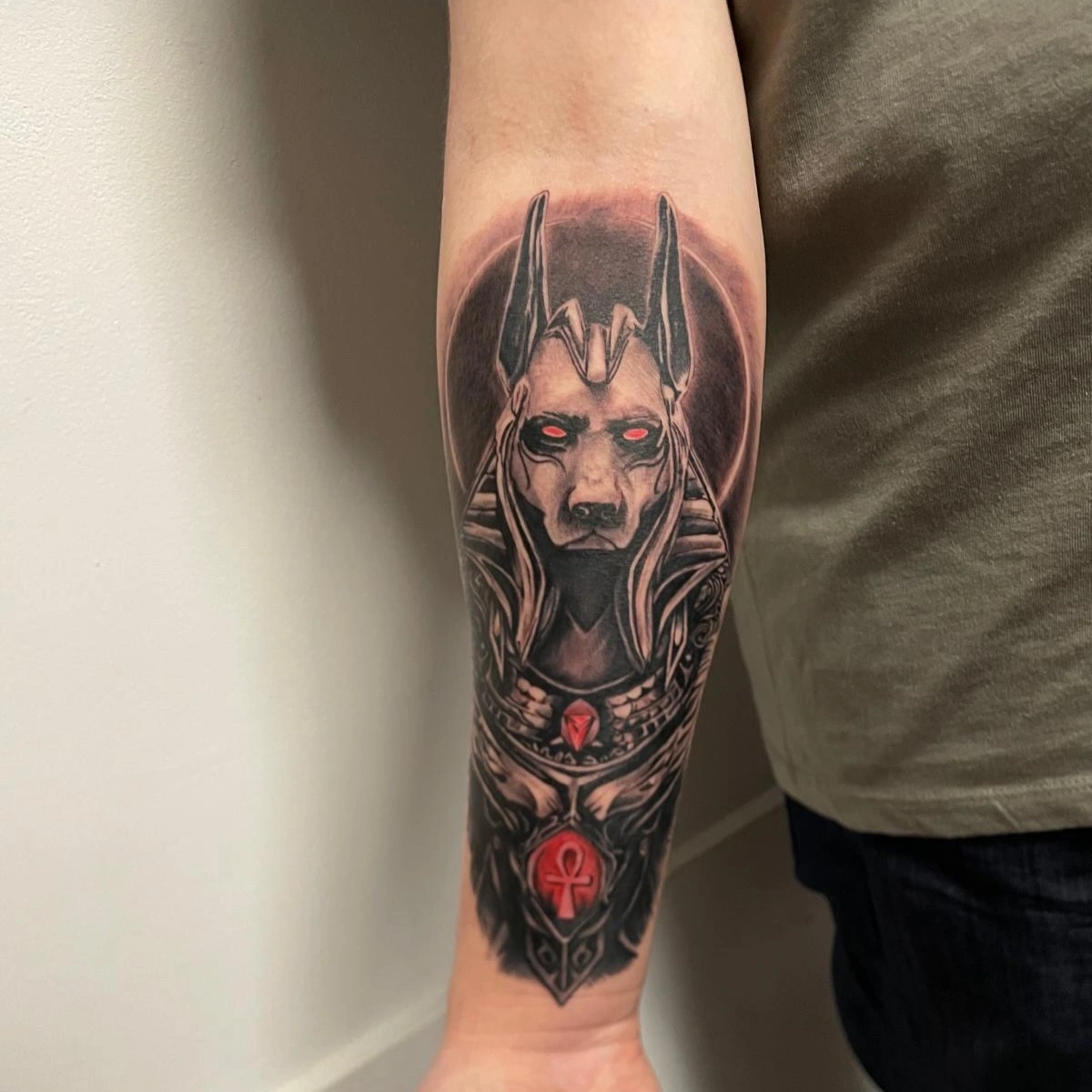 Tatuaj cu Anubis, zeul egiptean, pe antebrațul unei persoane.