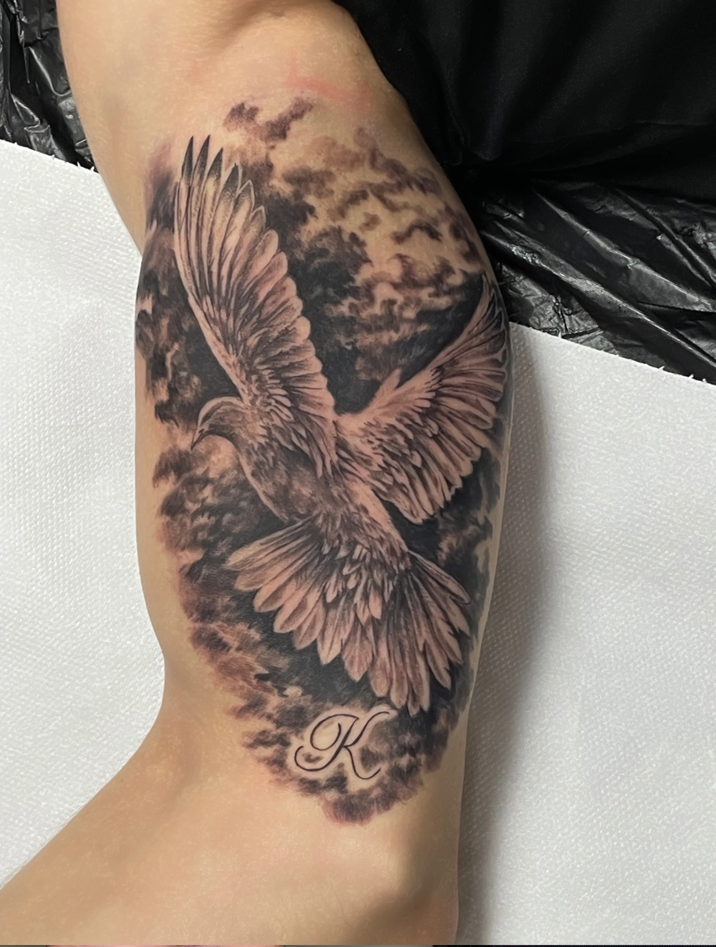 Tatuaj detaliat cu pasăre în zbor și litera K