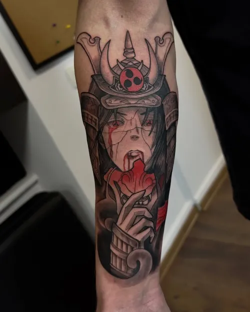 Tatuaj color pe antebraț reprezentând un personaj anime cu cască de samurai, păr negru, ochi roșii și accente de sânge roșu.