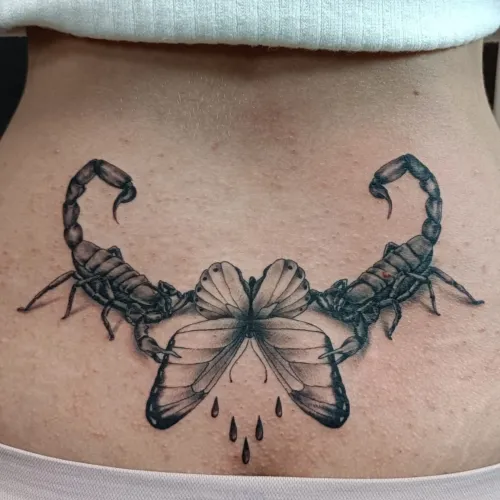 Tatuaj alb-negru plasat sub bust, cu doi scorpioni simetrici orientați spre un fluture central, realizat cu linii fine și umbre realiste.