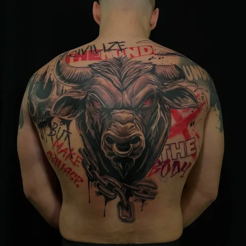 Tatuaj mare pe spate cu cap de taur realist, ochi roșii, lanț la bază și elemente graffiti negre și roșii în fundal.